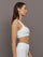 Model wears ribbed, white racerback sports bra with a fitted design and square neckline.
