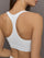 Model wears ribbed, white racerback sports bra with a fitted design and square neckline.
