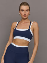 Model wears a white with navy overlay sports bra perfect for medium impact activities. 