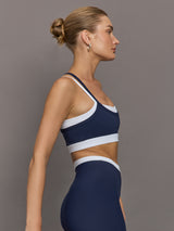 Model wears a white with navy overlay sports bra perfect for medium impact activities. 
