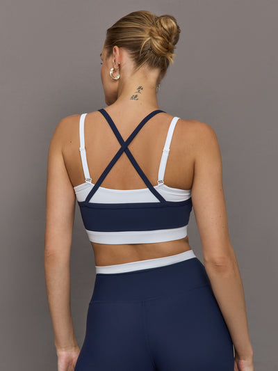 Model wears a white with navy overlay sports bra perfect for medium impact activities. 