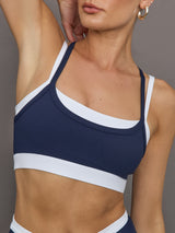 Model wears a white with navy overlay sports bra perfect for medium impact activities. 
