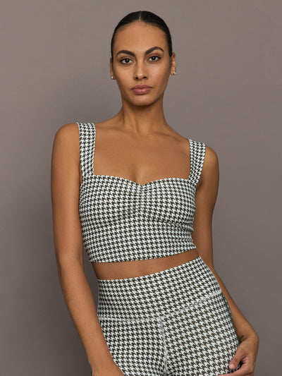 Model wearing houndstooth sports bra with wide straps and sweetheart neckline, front view close-up.