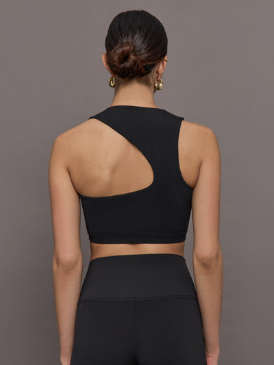 Model wears a cropped black athleisure tank with an asymmetrical racerback. 