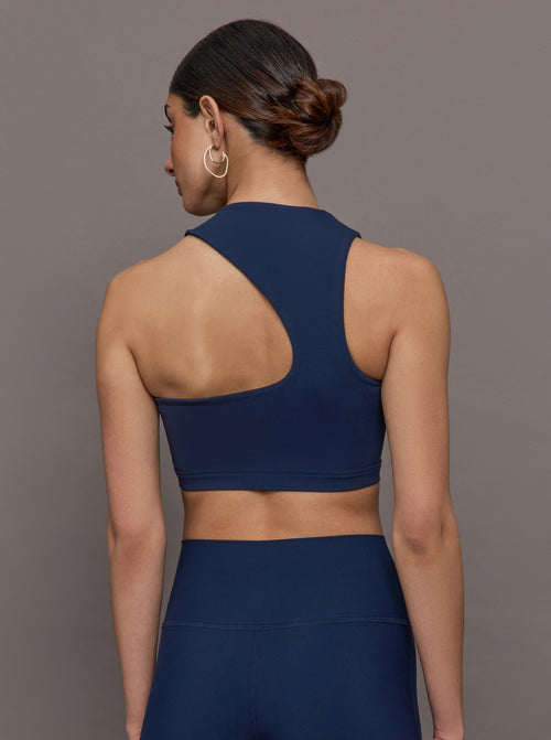 Model wears a cropped navy athleisure tank with an asymmetrical racerback. 