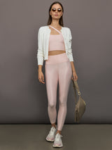 Model wears shiny, asymmetrical one-shoulder bra top in light pink, with a smooth, reflective fabric.