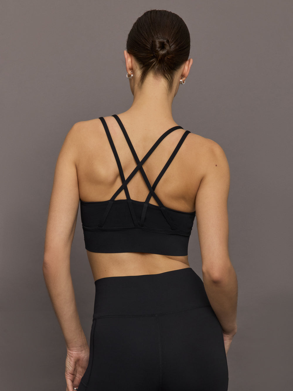 Model is wearing Diamond Compression Multi Strap Active Bra in Black, back strap detail.