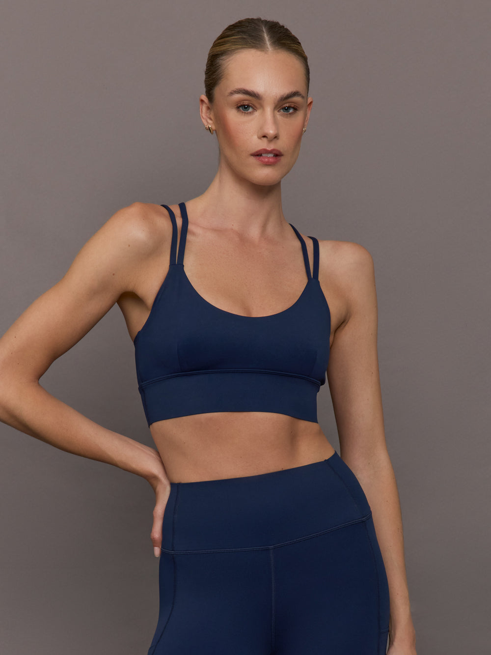 Model is wearing navy multi strap sports bra, front view.