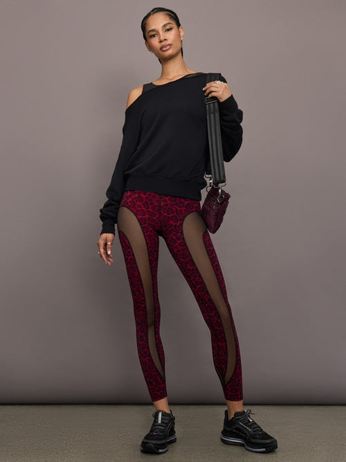 Model is wearing the Red Leopard Melt leggings with a black sweatshirt, full-body view.