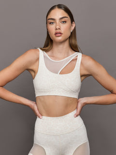 Model wears Snow leopard sports bra with a white mesh overlay, featuring a scoop neckline, wide straps.