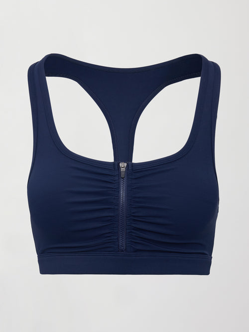 Model wearing a navy blue sports bra with zipper in the middle.