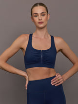 Model wearing a navy blue sports bra with zipper in the middle.