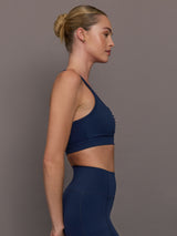 Model wearing a navy blue sports bra with zipper in the middle.