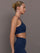 Model wearing a navy blue sports bra with zipper in the middle.