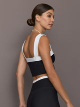 Model is wearing a black and white square-neck longline contrast bra top with wide straps and low square back, showing fitted side profile, styled with matching leggings, side view.