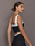 Model is wearing a black and white square-neck longline contrast bra top with wide straps and low square back, showing fitted side profile, styled with matching leggings, side view.