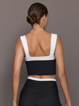 Model is wearing a black and white square-neck longline contrast bra top with wide straps and a low square back, styled with matching leggings, back view.