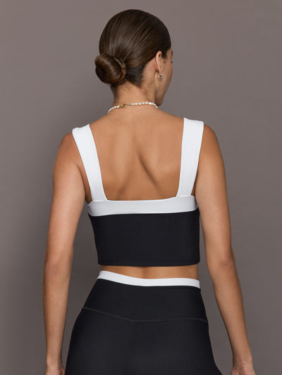 Model is wearing a black and white square-neck longline contrast bra top with wide straps and a low square back, styled with matching leggings, back view.
