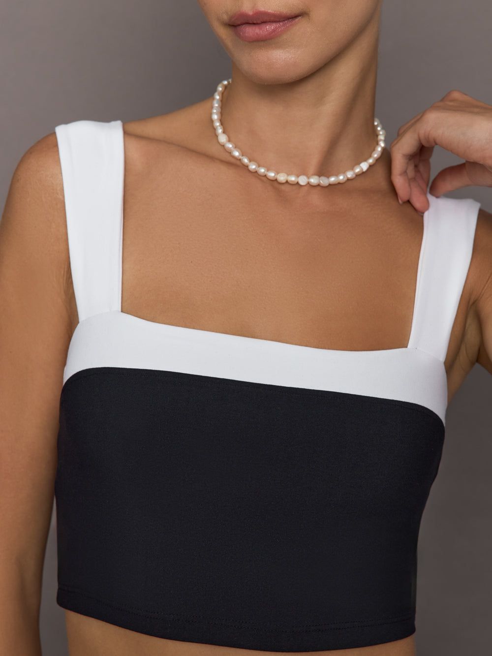 Model is wearing a black and white square-neck longline contrast bra top with wide straps, close-up front view.