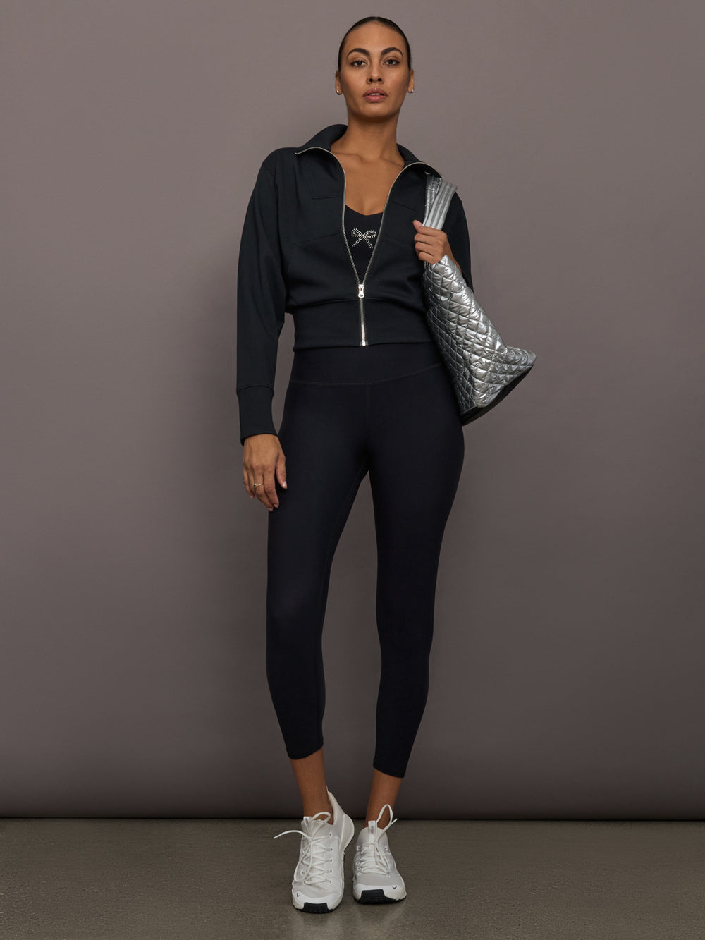 Rhinestone Bow Bra in Melt Black styled with high-waisted leggings, black zip jacket, and silver tote.