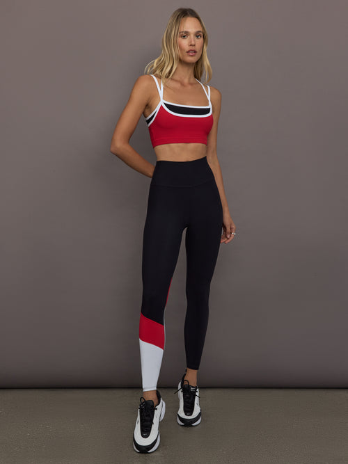 Model is wearing Melt Double Layered Sports Bra in Black, Crimson, and White Binding, full body front view styled with leggings.