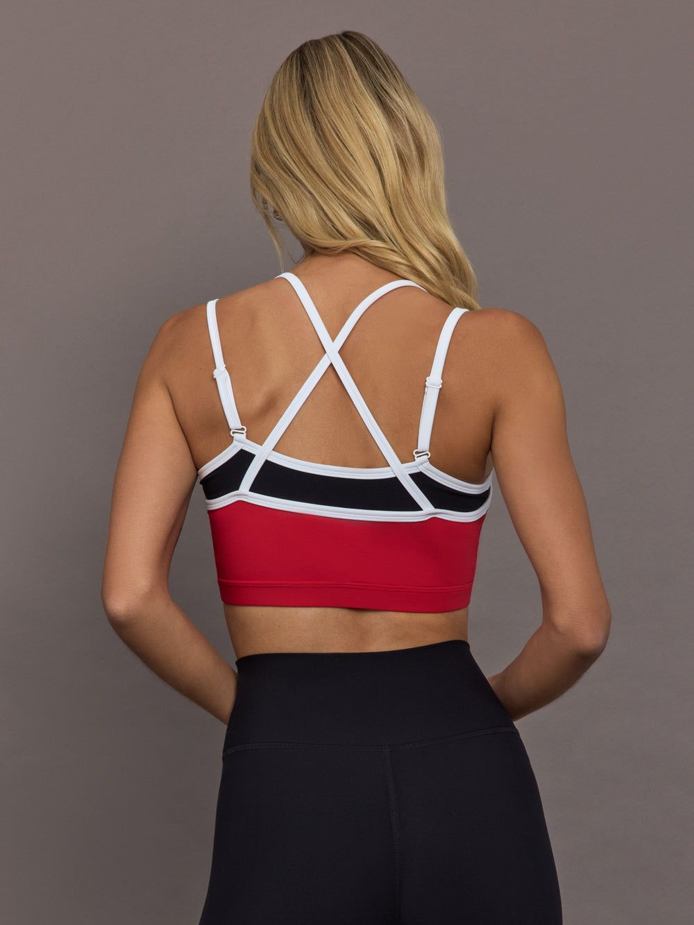Model is wearing Melt Double Layered Sports Bra in Black, Crimson, and White Binding, back view with crossed adjustable straps.