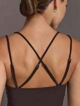Model is wearing a dark brown square-neck tank top with thin double straps and adjustable crisscross back detail, close-up back view.