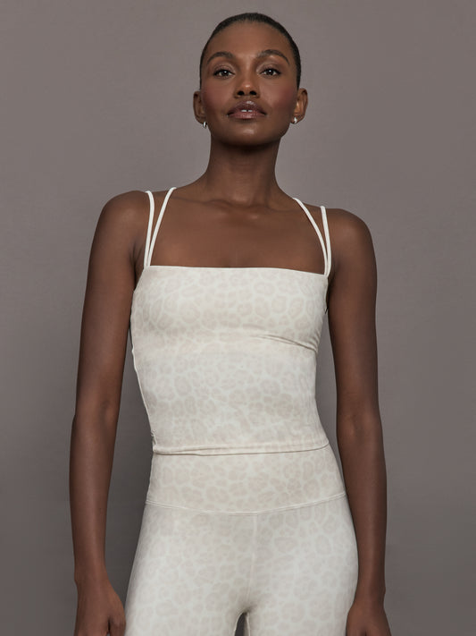 Model wears a buttery soft athleisure double strapped tank with cross back in a snow leopard print. 