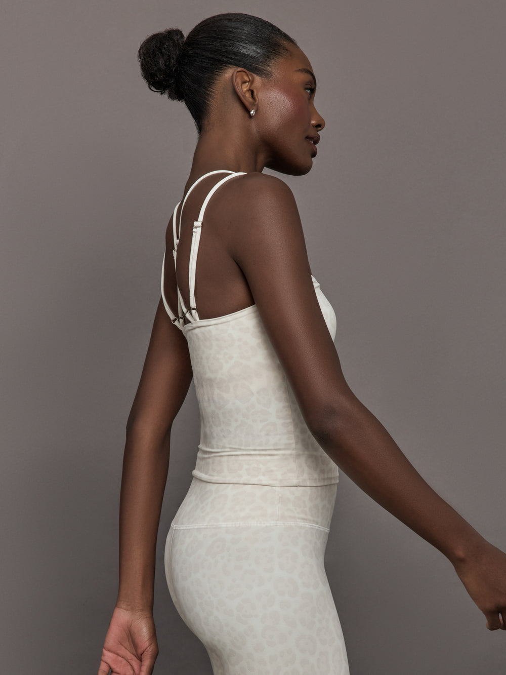 Model wears a buttery soft athleisure double strapped tank with cross back in a snow leopard print. 