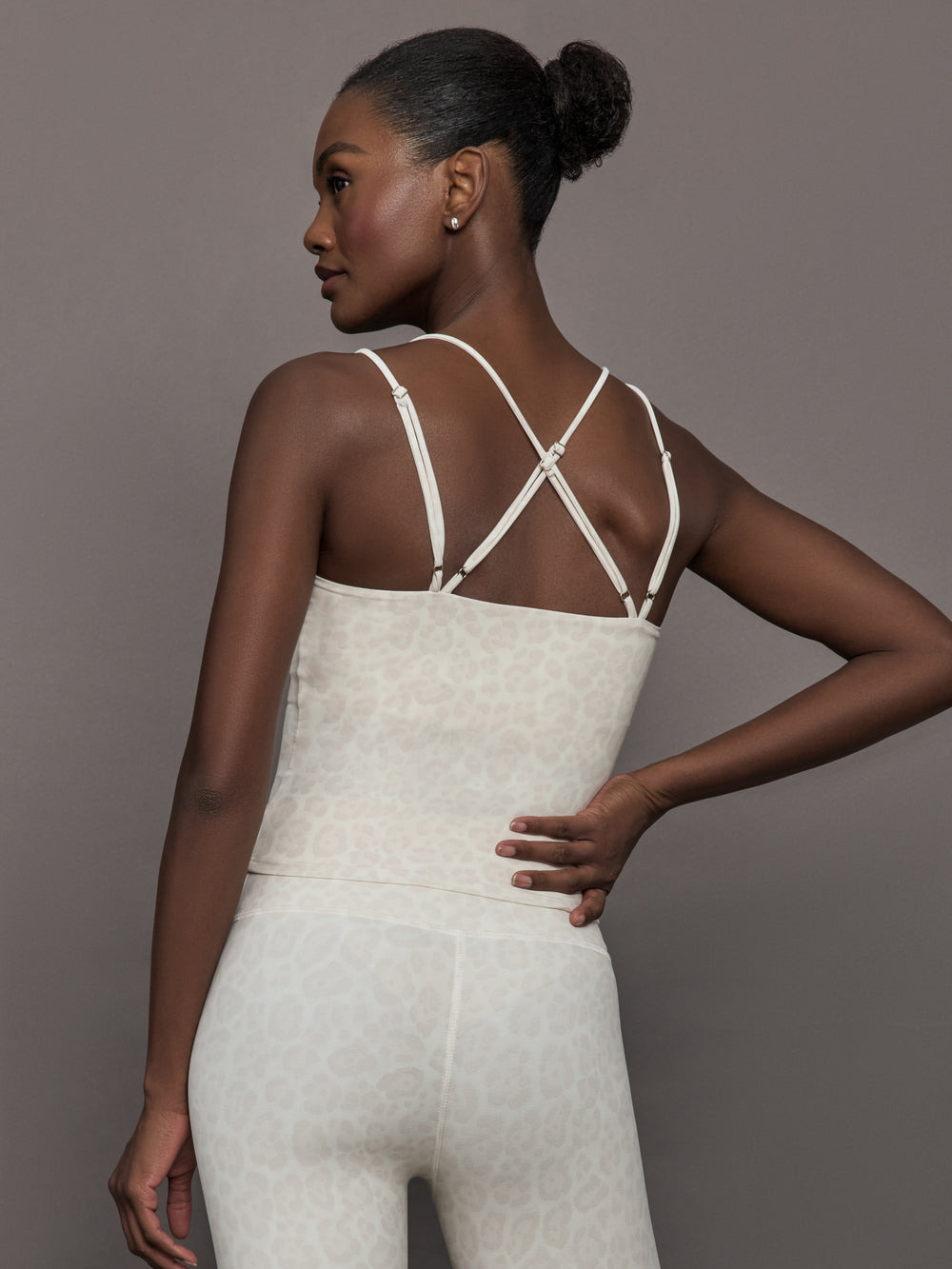 Model wears a buttery soft athleisure double strapped tank with cross back in a snow leopard print. 