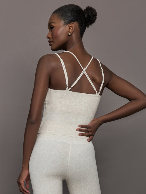 Model wears a buttery soft athleisure double strapped tank with cross back in a snow leopard print. 