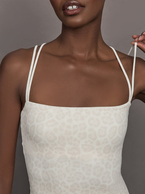 Model wears a buttery soft athleisure double strapped tank with cross back in a snow leopard print. 