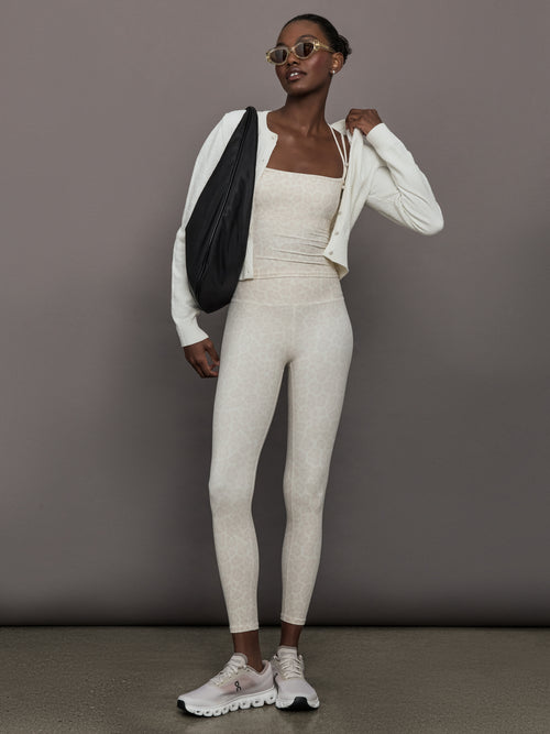 Model wears a buttery soft athleisure double strapped tank with cross back in a snow leopard print. 