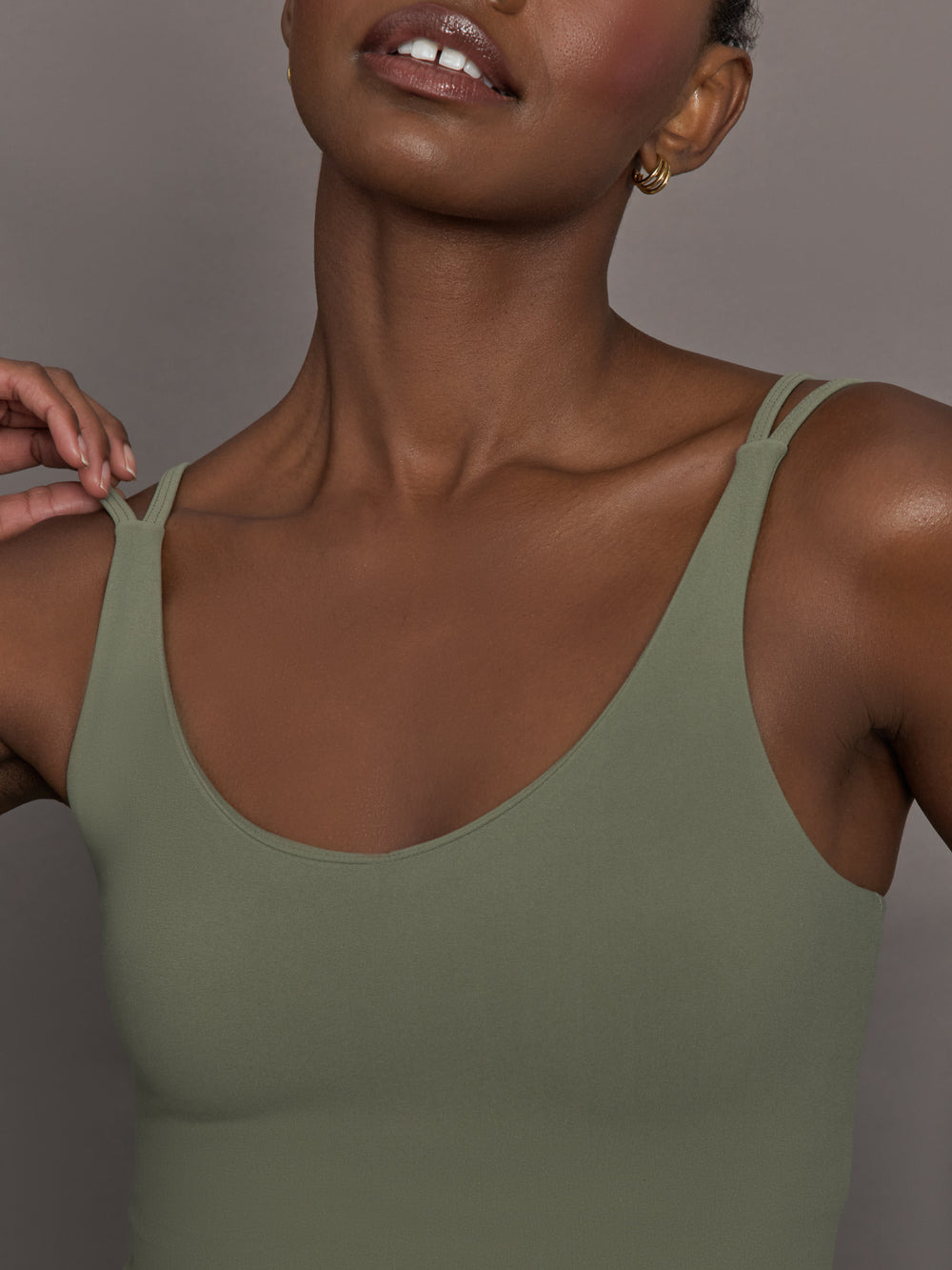 Model wears an army green tank top with double straps. 