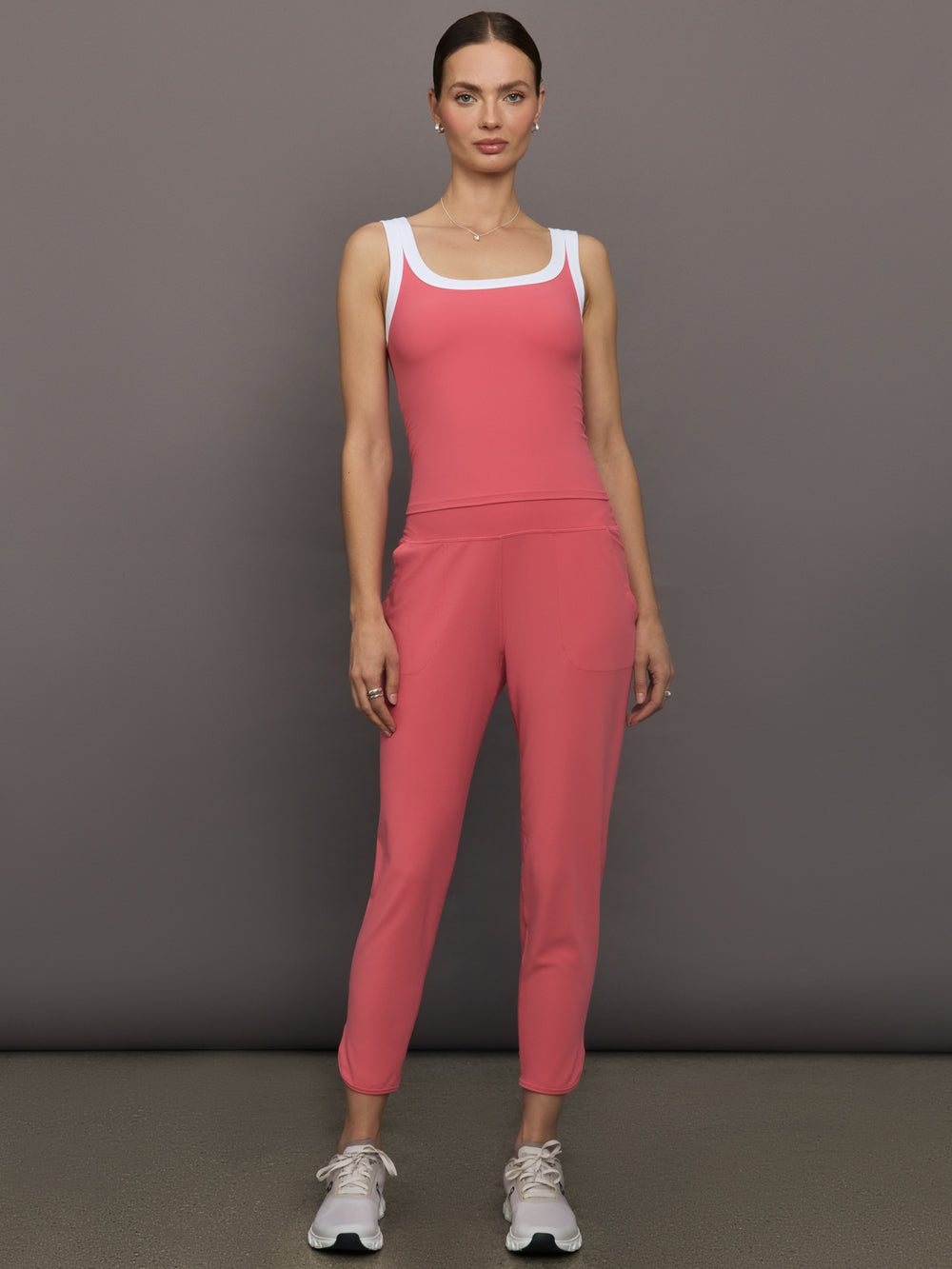 Model wears a rosewood colored tank top with thick white straps and a scoop tank neckline.