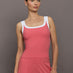 Model wears a rosewood colored tank top with thick white straps and a scoop tank neckline.