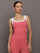 Model wears a rosewood colored tank top with thick white straps and a scoop tank neckline.