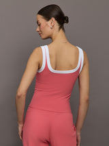 Model wears a rosewood colored tank top with thick white straps and a scoop tank neckline.