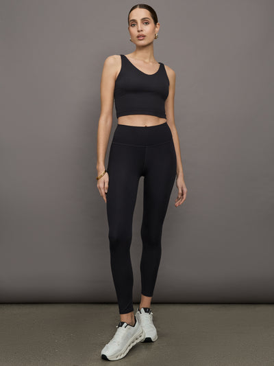 Model wears a black v neck cropped tank top with double straps in back. 