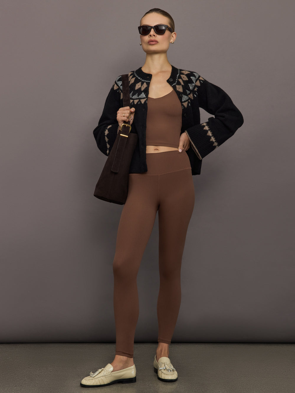 Full outfit shot of women wearing cocoa brown ribbed melt v-neck tank with matching leggings, styled under black patterned cardigan and loafers.