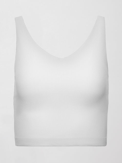Model wears white ribbed V-neck tank with a sculpted and cropped fit.
