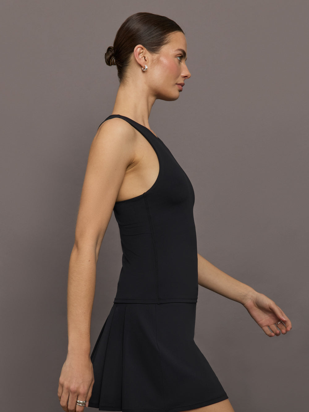 Model wears black high-neck tank with a racerback design and smooth, fitted finish.
