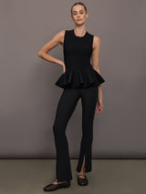 Woman wearing a sleeveless black peplum top against a gray background.