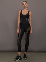 Model wears a black tank top with laser cutout paneling along riblines bilaterally. 