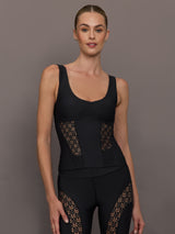 Model wears a black tank top with laser cutout paneling along riblines bilaterally. 