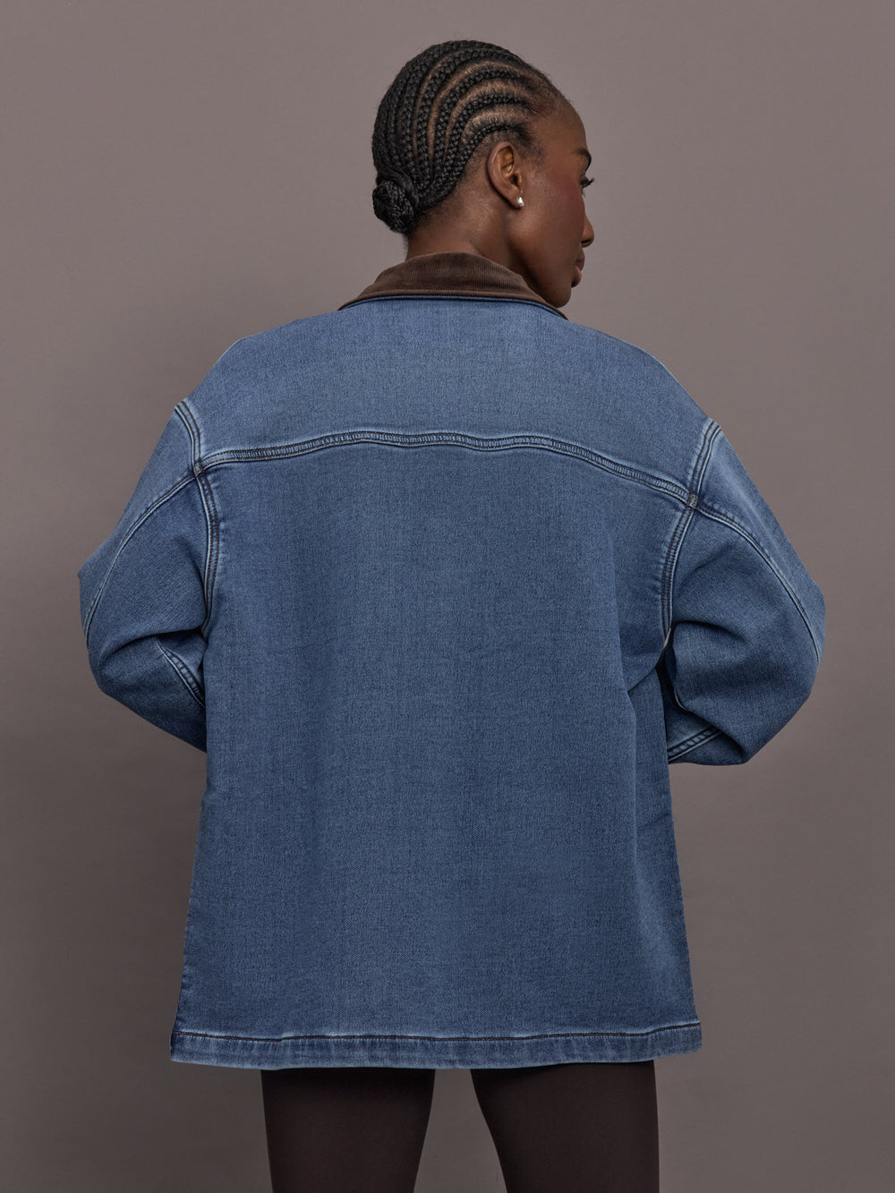 Model is wearing the Denim Barn Jacket in Dark Wash, back view.