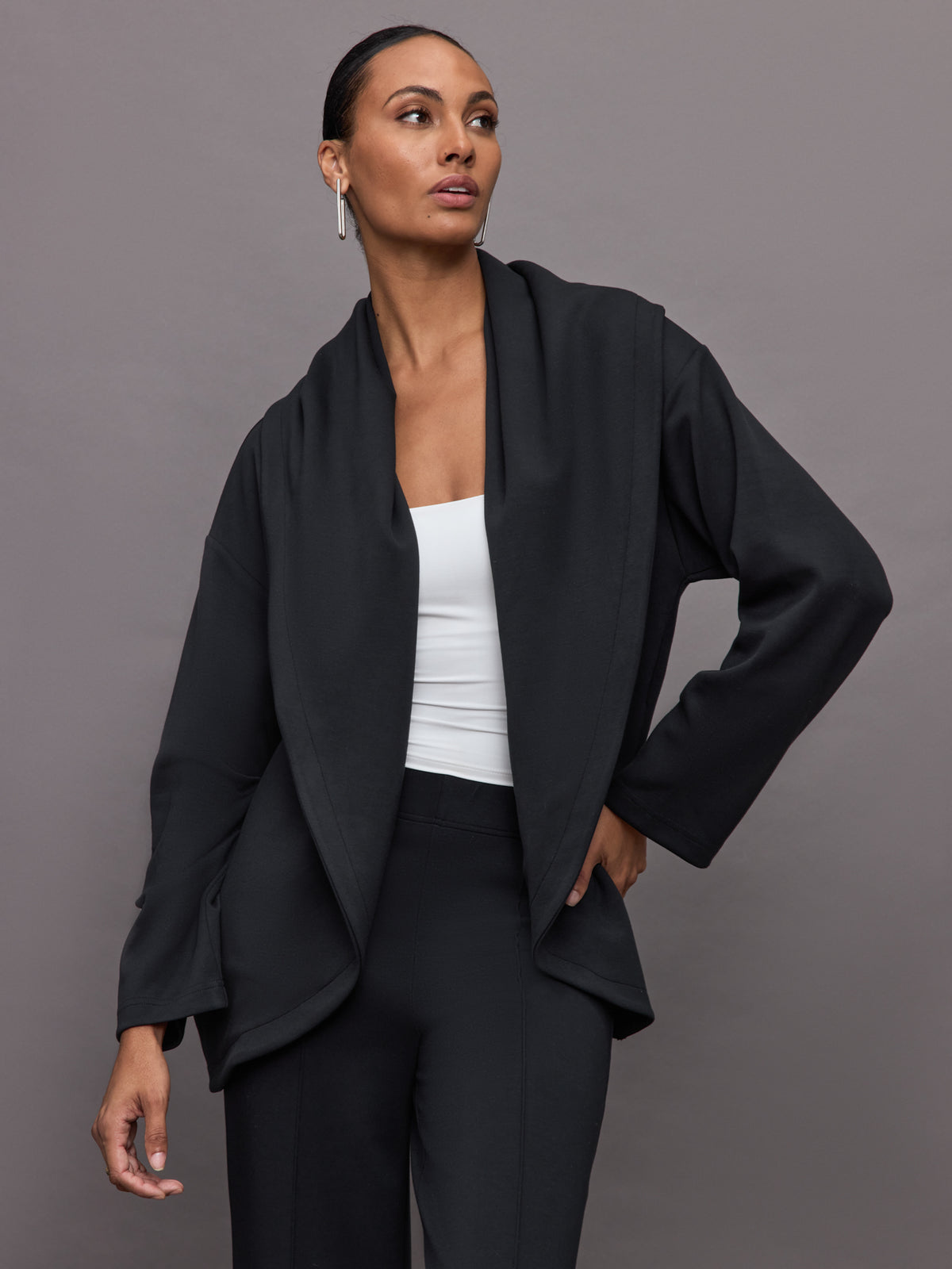 Model wears black open-front cardigan with a loose, draped fit, wide bell sleeves, and side pockets.