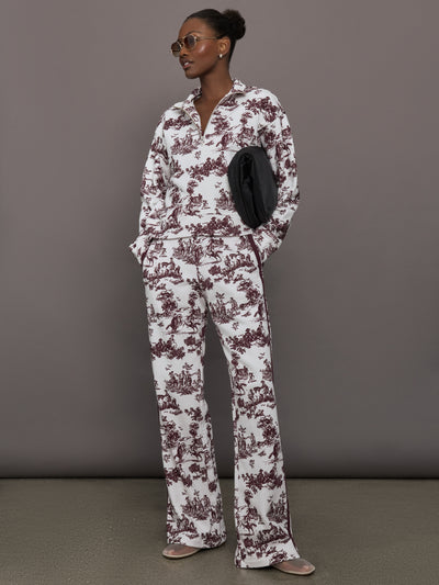 Model wears a burgundy toile printed mock neck zip up long sleeve track sweatshirt.