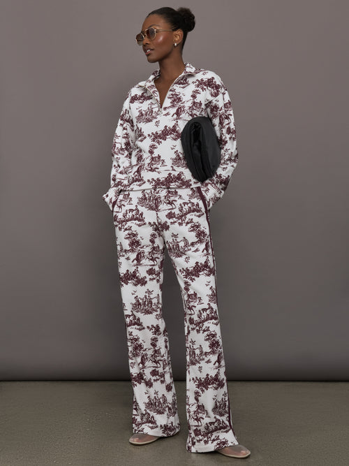 Model wears a burgundy toile printed mock neck zip up long sleeve track sweatshirt.