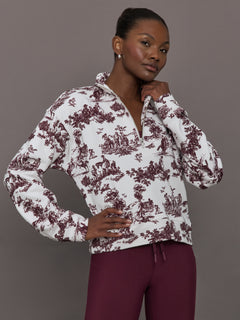 Model wears a burgundy toile printed mock neck zip up long sleeve track sweatshirt.